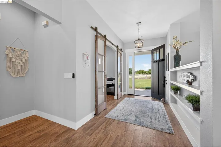 Entrance foyer featuring a barn door, hardwood / wood-style floors, and a chandelier