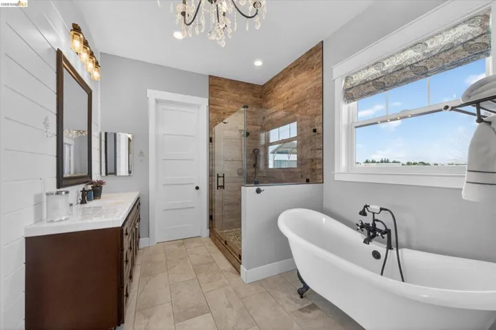 Bathroom with a shower stall, a freestanding bath, double vanity, and a chandelier