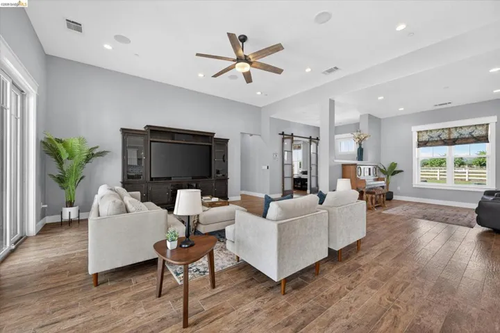 Living room featuring a barn door, hardwood / wood-style floors, a ceiling fan, and recessed lighting