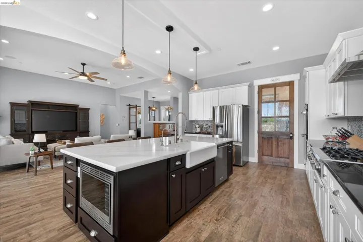 Dual tone kitchen with open floor plan, pendant lighting, stainless steel appliances, a center island with sink, and two tone​​‌​​​​‌​​‌‌​​‌​​​‌‌​​​‌​​‌‌​​‌‌​​‌‌​​​​ cabinets