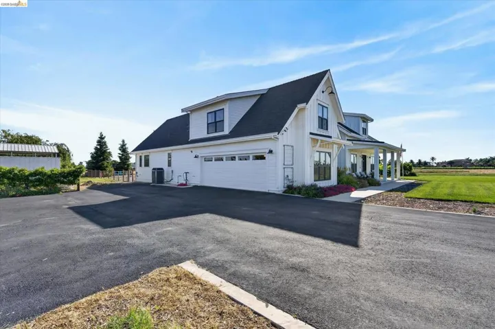 View of side of property with asphalt driveway, a shingled roof, a porch, and board and batten siding