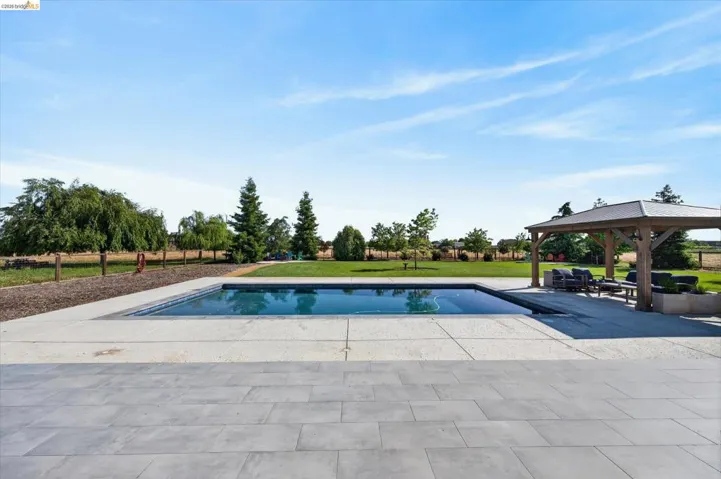 Swimming pool featuring a patio, a gazebo, and a yard