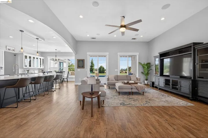 Living area with ceiling fan, arched walkways, hardwood / wood-style flooring, and hanging lights