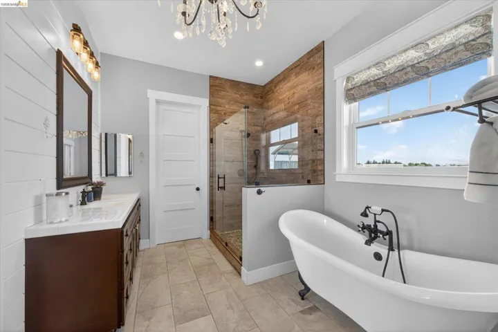 Bathroom featuring a stall shower, a freestanding tub, double vanity, and hanging chandelier