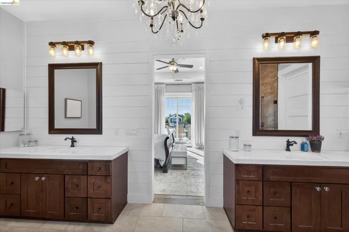 Ensuite bathroom with two vanities, hanging lights, and wood walls