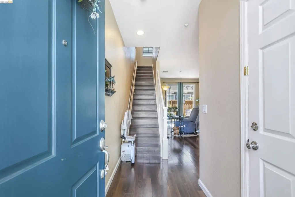 Foyer showcasing dark wood-finish flooring, a multi-story staircase with white risers and wooden treads, recessed lighting, and a neutral wall color