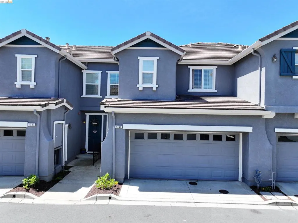 Contemporary stucco exterior with a tile roof, featuring white-trimmed windows and an attached two-car garage
