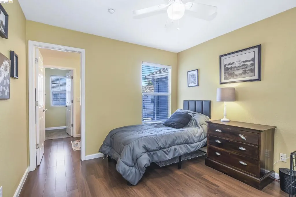 Bedroom featuring wood-finish flooring, a ceiling fan, and a window with blinds