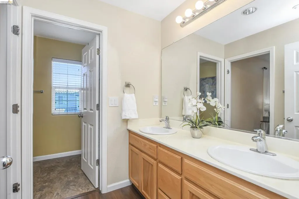 Double vanity with light wood cabinetry, white countertops, and dual undermount sinks