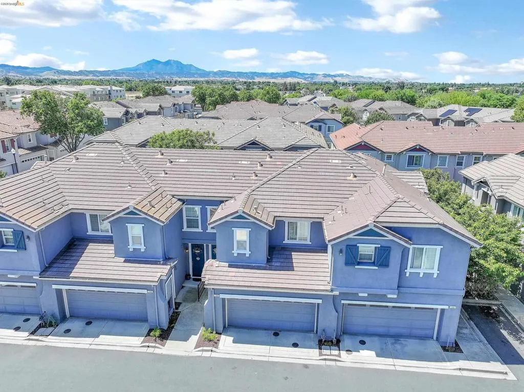 Multi-level townhouse property featuring tile roofing and blue exterior siding