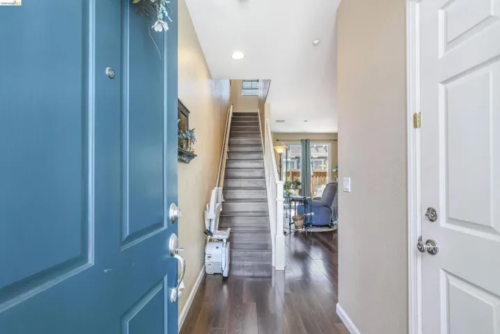 Foyer showcasing dark wood-finish flooring, a multi-story staircase with white risers and wooden treads, recessed lighting, and a neutral wall color