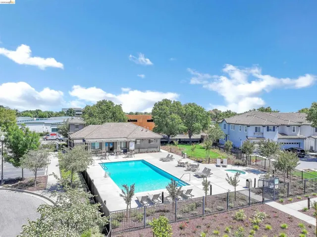 Community swimming pool with surrounding lounge deck, spa, and adjacent club house