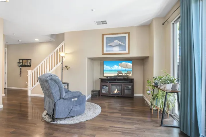 Living area featuring wood-finish flooring, a built-in media niche with a fireplace, and a light-toned wall finish