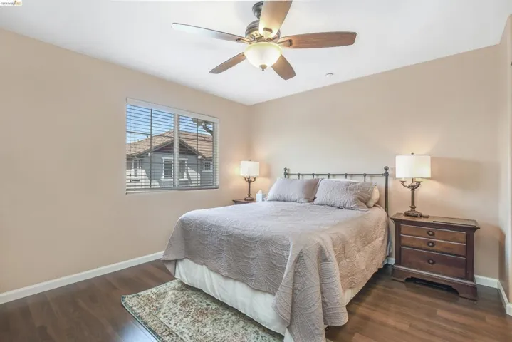 Bedroom featuring wood-finish flooring, a ceiling fan with integrated lighting, and a window with horizontal blinds
