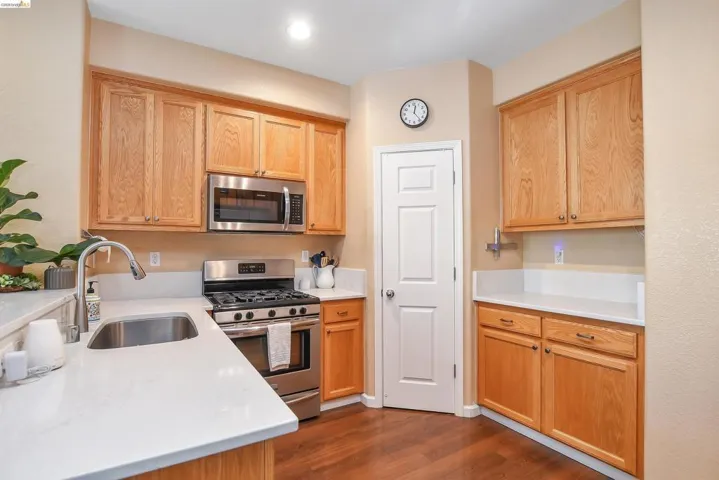 Kitchen featuring light wood cabinetry, stainless steel appliances, white countertops, and wood-finish flooring