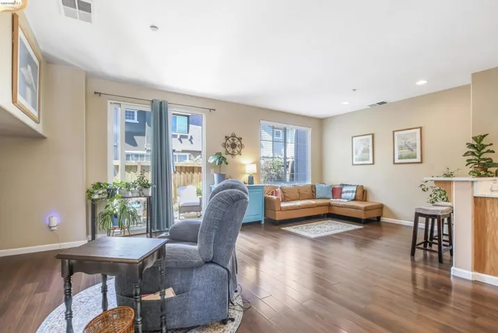 Spacious living area featuring rich wood-finish flooring, recessed lighting, and neutral wall tones