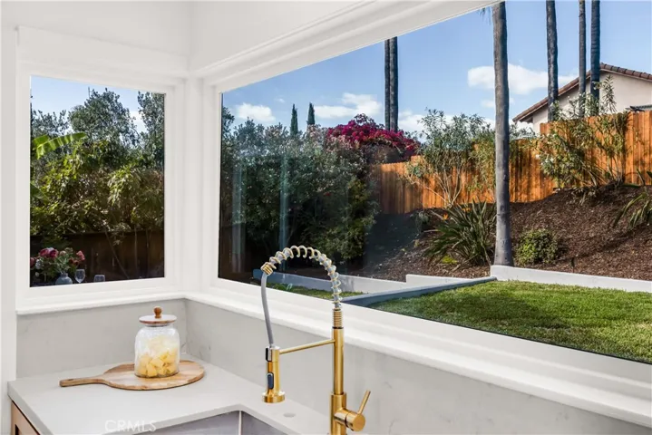 Close-up view of the kitchen sink with a bright, scenic backdrop of the backyard, providing a peaceful view while cooking.