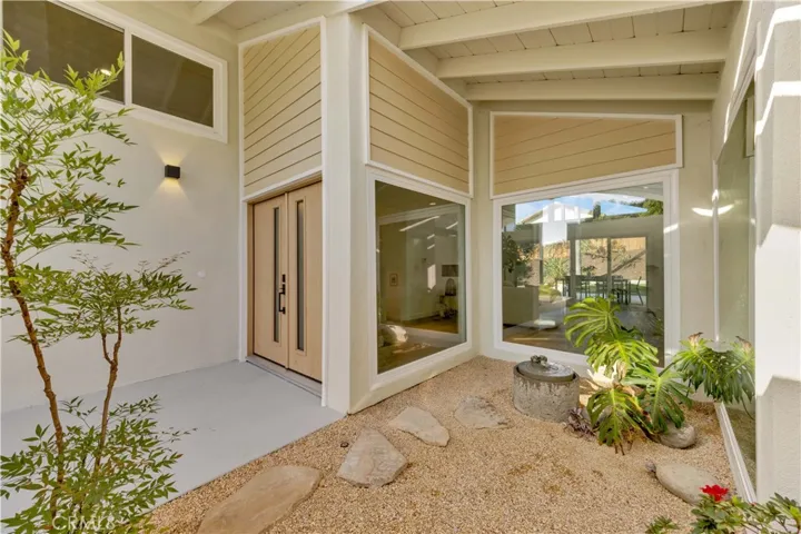 A welcoming front entryway, showcasing the stylish design with a large windows and a thoughtfully lanscaped area leading up to the door.