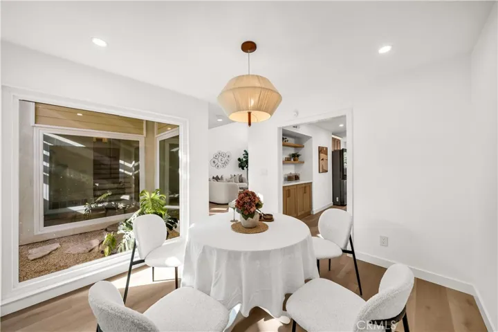Charming dining area with natural light flowing through a large window, showcasing a peaceful outdoor space and inviting atmosphere for dining and gatherings.