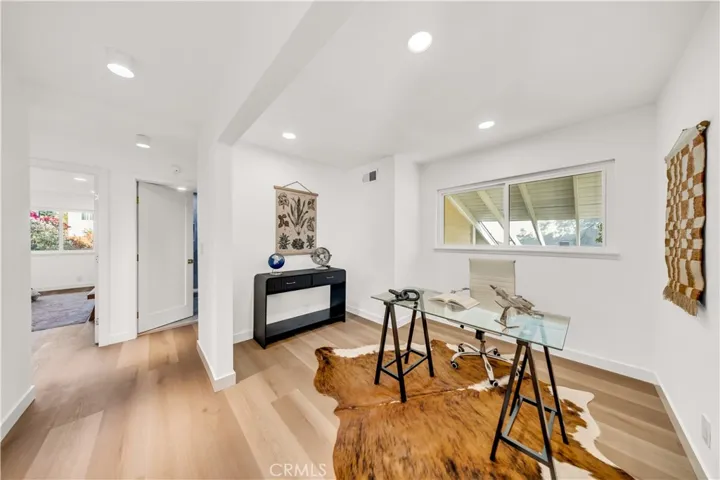A bright and spacious home office, designed for productivity, featuring modern furnishings and natural light streaming in through large windows.