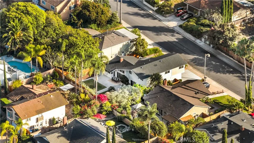 Bird's eye view of the property and surrounding neighborhood, highlighting the beautiful landscaping and close proximity to the street.