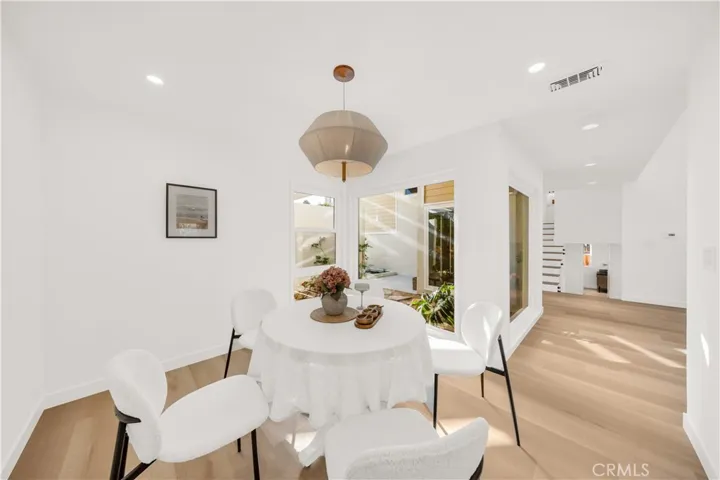 Alternate view of the dining space, highlighting the open flow into the kitchen area and bringing the outdoors in with large windows showcasing the tranquil garden.