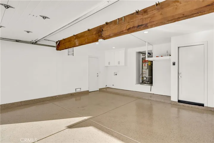 Spacious garage with epoxy-coated floor, recessed lighting, and EV charger for added convenience.
