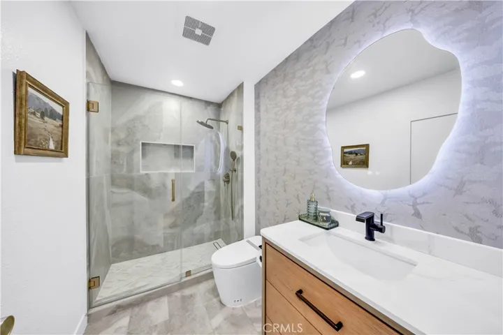 Upstairs bathroom featuring modern finishes, a stylish walk-in shower, and a sleek vanity with an illuminated mirror.