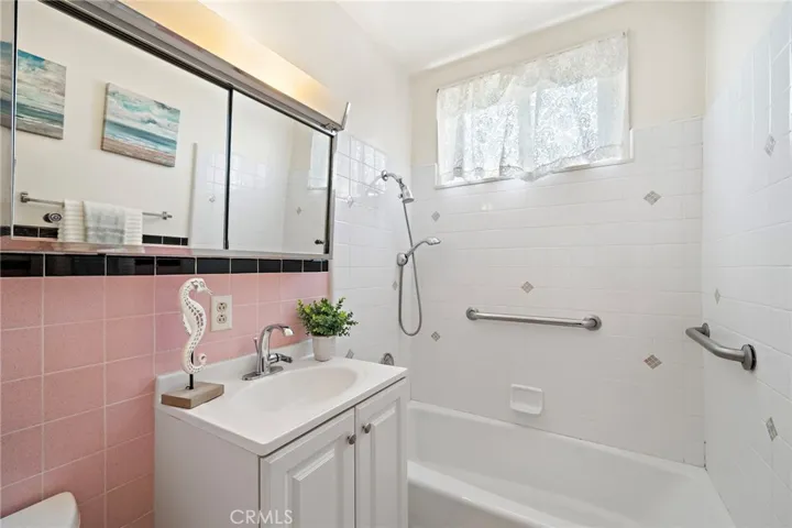 Adorable Bathroom with Tile Floor, Tile Walls, and a Tiled Tub/Shower Combo with Grab Bars