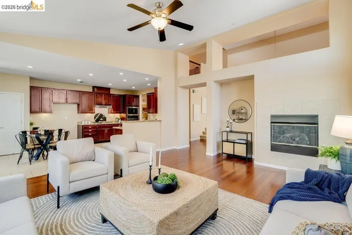 Living area featuring ceiling fan, a tiled fireplace, wood finished floors, recessed lighting, and lofted ceiling