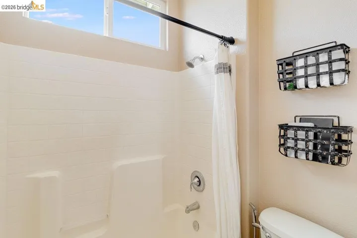 Bathroom featuring shower / tub combo with curtain and a textured wall