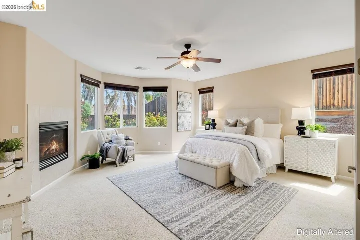 Carpeted bedroom featuring a fireplace, a ceiling fan, and radiator heating unit