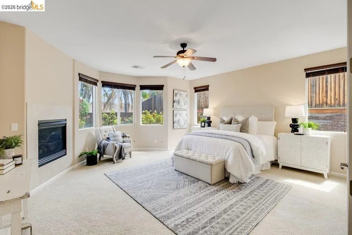 Carpeted bedroom with a tiled fireplace and a ceiling fan