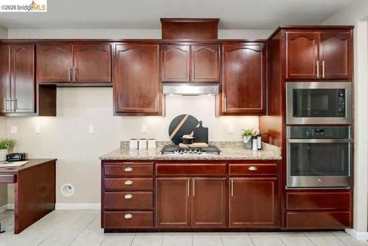 Kitchen featuring stainless steel appliances, light stone countertops, and light tile patterned flooring