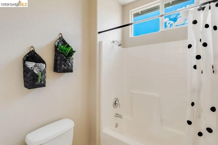 Bathroom featuring a textured wall and shower / tub combo with curtain