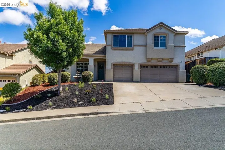 View of front of house featuring a garage, concrete driveway, and stucco siding