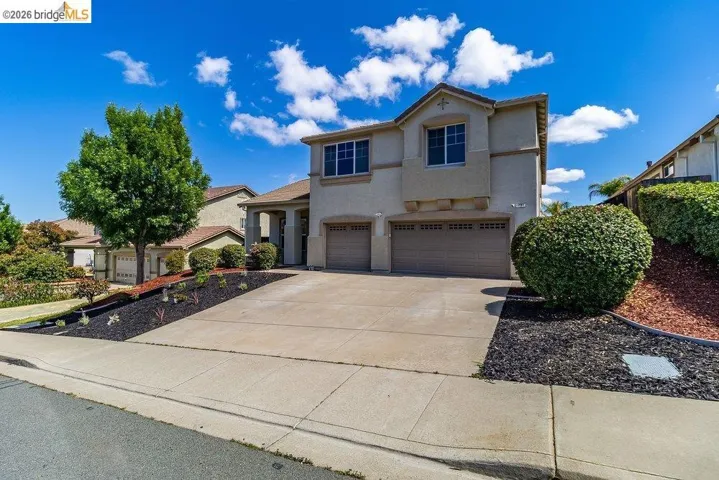 View of front facade featuring a garage, stucco siding, and concrete driveway