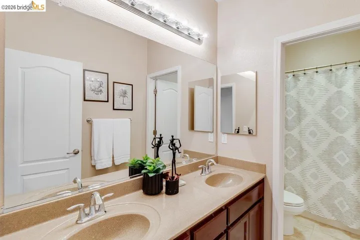 Bathroom with double vanity, a shower with curtain, and light tile patterned flooring