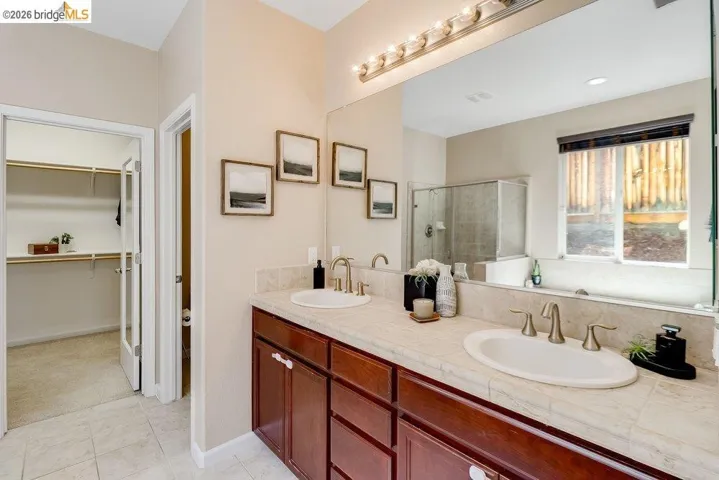 Bathroom with double vanity, a walk in closet, and a shower stall
