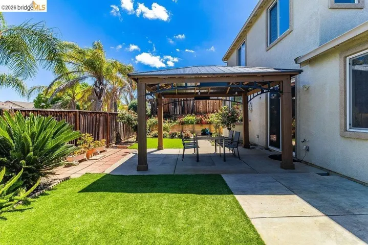 Fenced backyard featuring a patio area and a gazebo