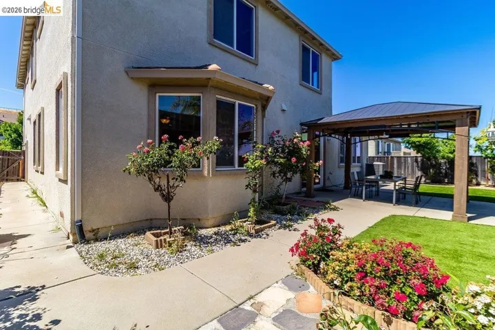Rear view of house with a fenced backyard, a gazebo, stucco siding, and a patio area