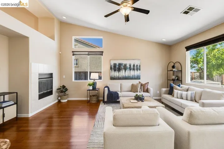 Living room with wood-type flooring, ceiling fan, a tile fireplace, vaulted ceiling, and recessed lighting