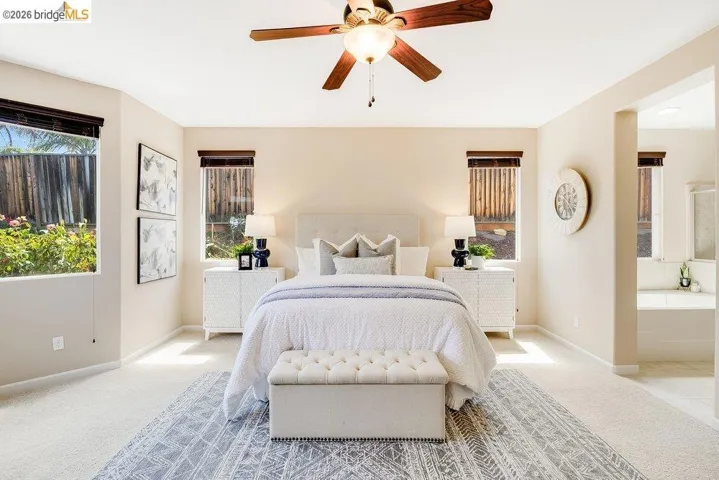 Carpeted bedroom featuring multiple windows and a ceiling fan