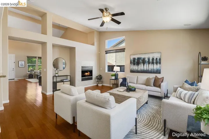 Living room featuring a tile fireplace, wood finished floors, lofted ceiling, and a ceiling fan
