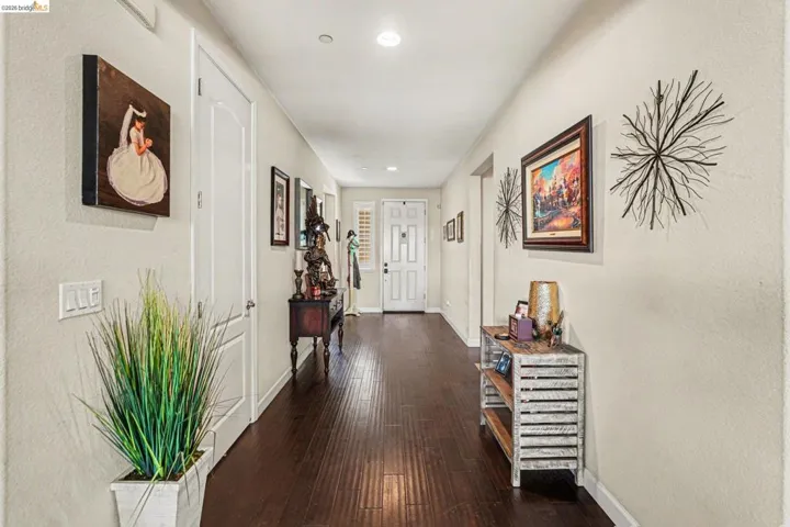Hallway with dark wood-style floors, recessed lighting, and a textured wall