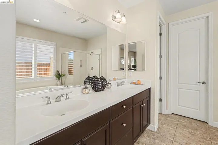 Bathroom featuring a shower stall, double vanity, a garden tub, and light tile patterned floors
