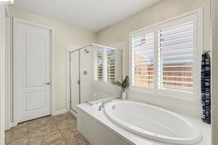 Full bath featuring a shower stall, a bath, and light tile patterned floors