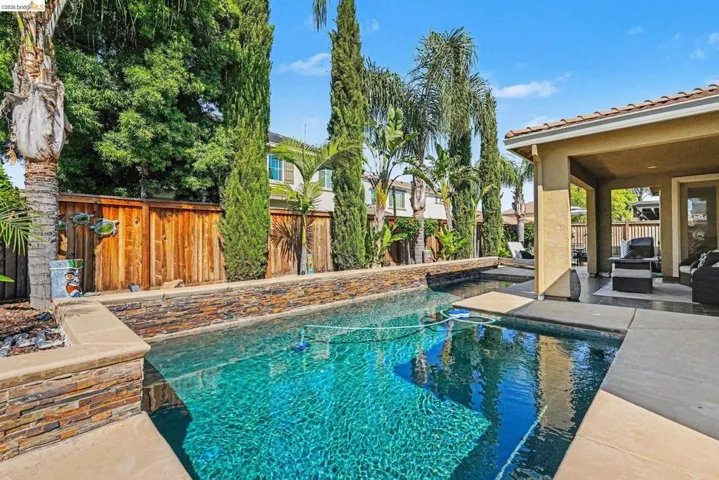View of swimming pool featuring patio surround and a fenced backyard