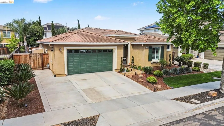 View of front of home with stucco siding, a garage, driveway, and a tile roof