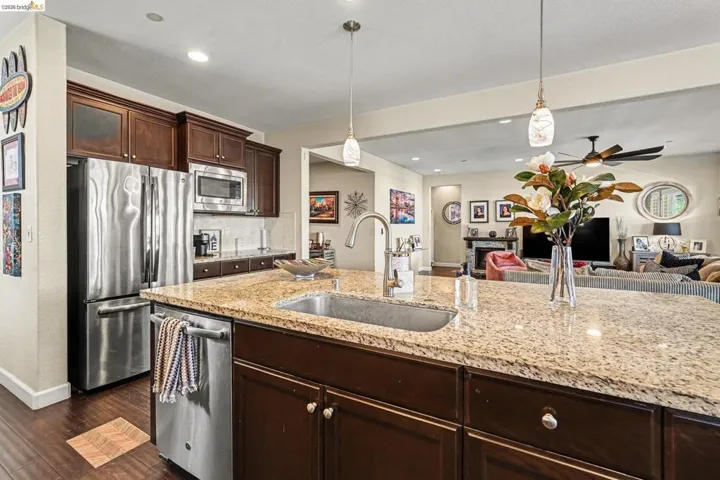 Kitchen featuring dark wood finish cabinets, open floor plan, stainless steel appliances, and decorative light fixtures